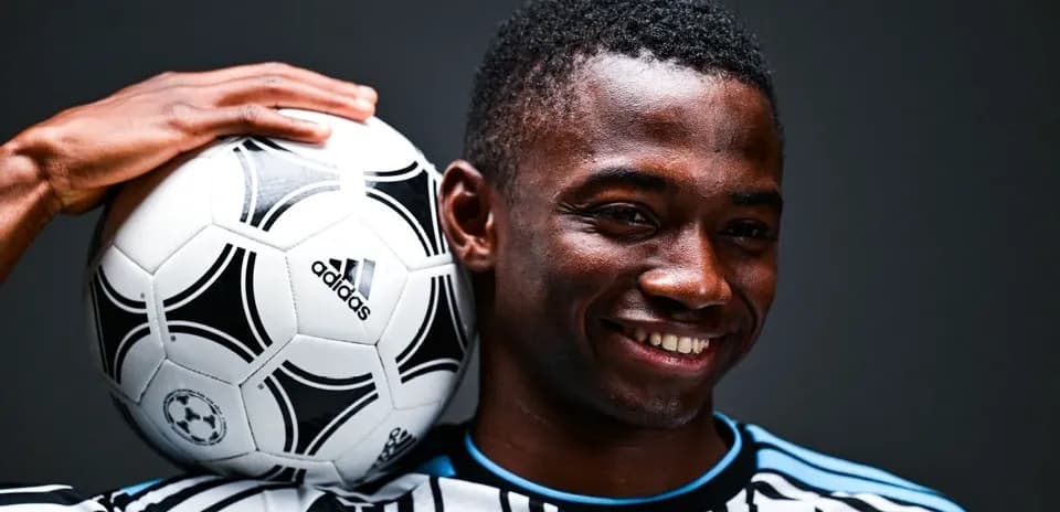 Jugador sosteniendo un balón de fútbol sobre su hombro