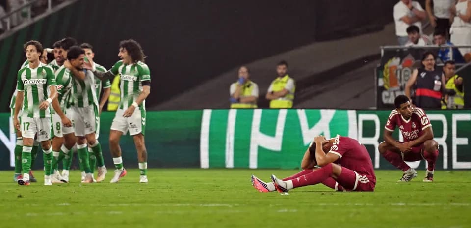 Jugadores de Betis celebrando gol, oponente desanimado