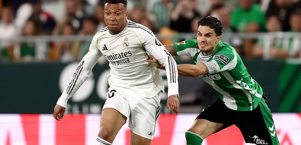 Mbappé dribbling while being challenged by defender