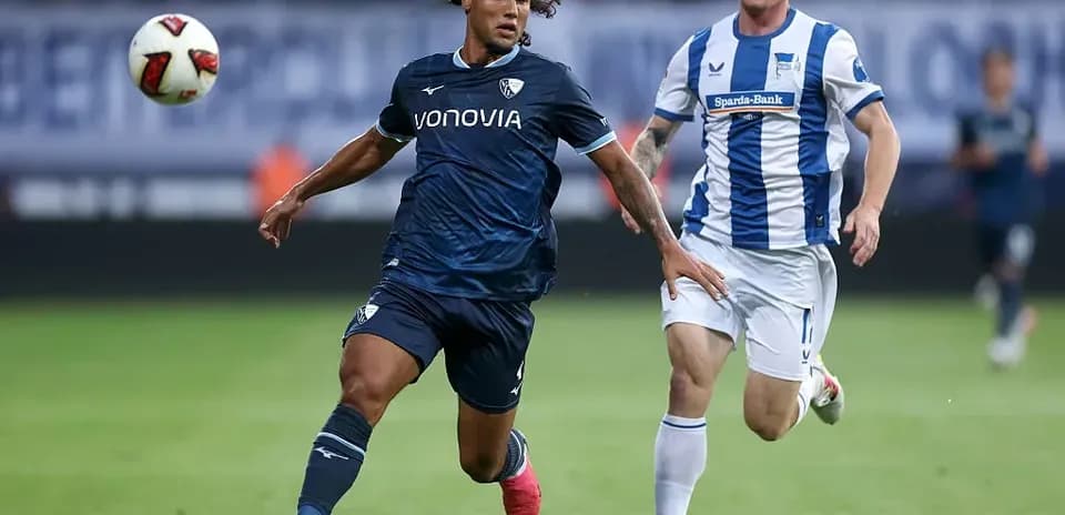 Jugador corriendo con el balón, seguido por oponente