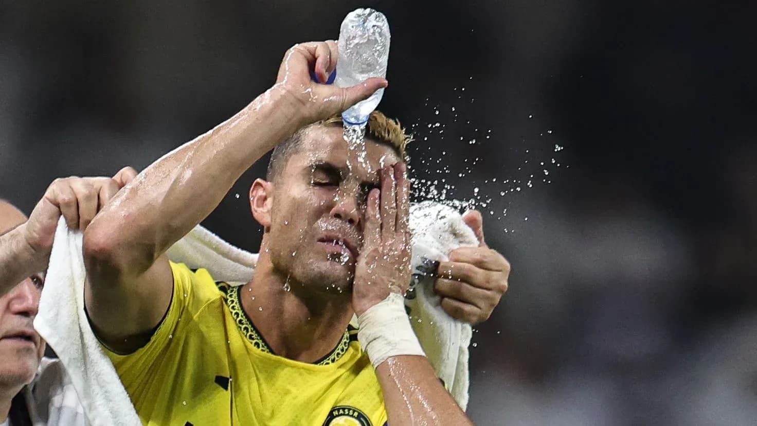 Jugador aplicando agua en su cara durante el partido