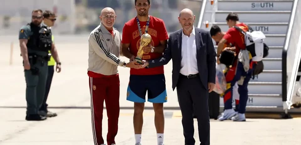 Jugador sosteniendo trofeo con directivos en aeropuerto