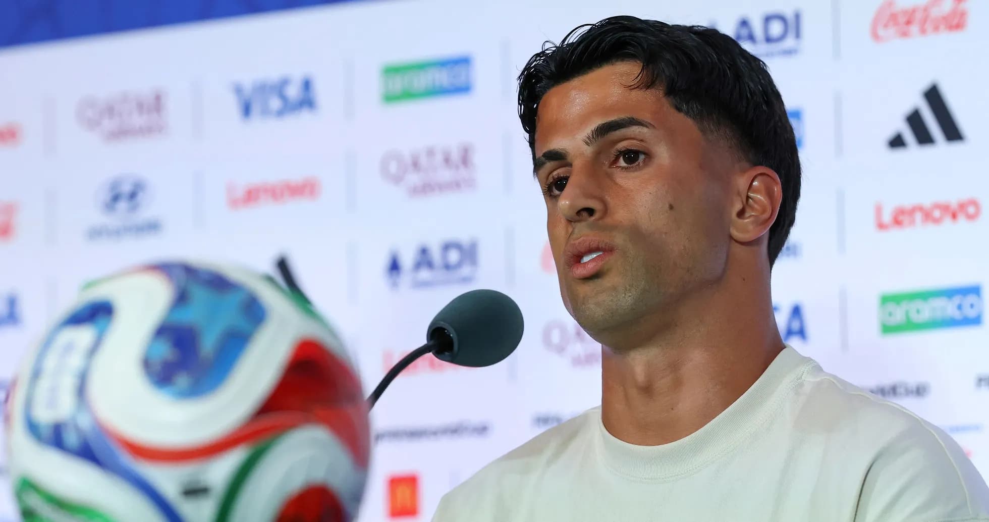 Jugador hablando en conferencia de prensa con balón