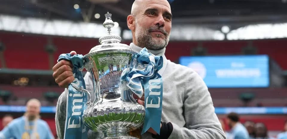 Entrenador sosteniendo trofeo en Wembley