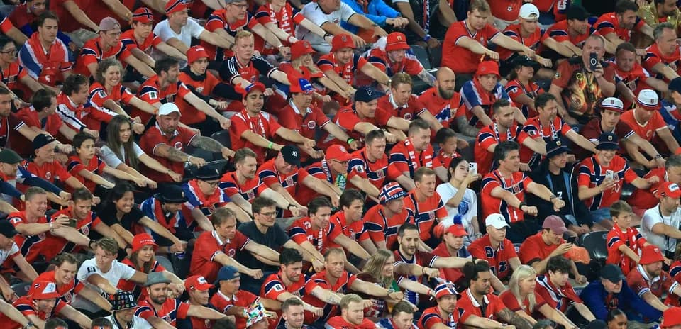 Aficionados animando en un estadio, vestidos de rojo