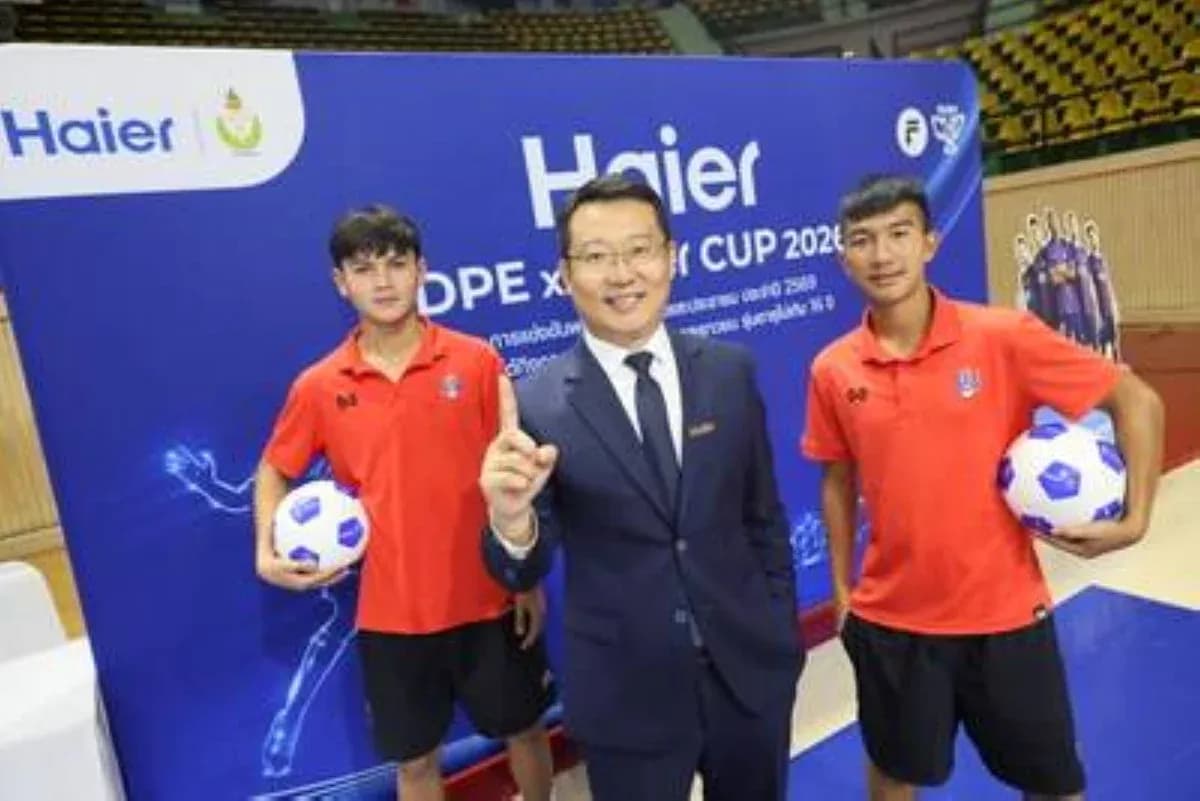 Tres personas posando con balones de fútbol en evento