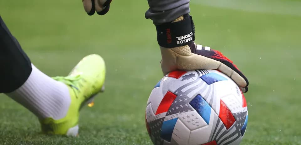Portero sosteniendo un balón de fútbol en el césped