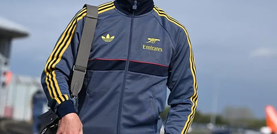 Jugador vestido con chándal y gorra en el aeropuerto