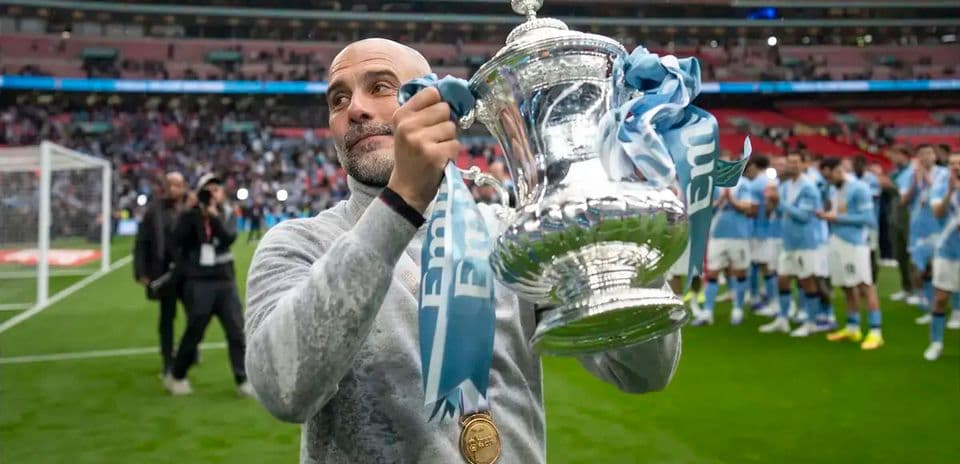 Entrenador sosteniendo trofeo en el campo de Wembley