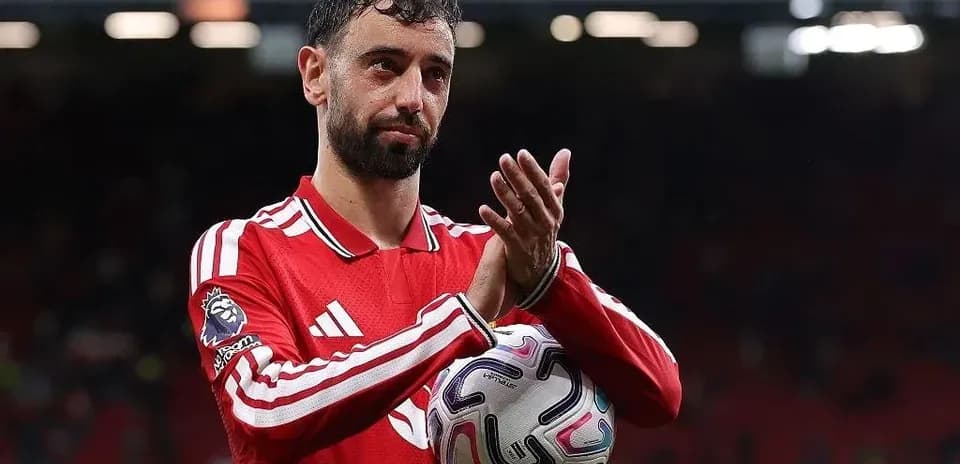 Jugador aplaudiendo con balón en mano en el estadio
