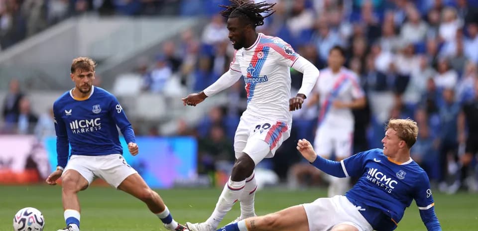 Jugador de Crystal Palace driblando entre dos defensores de Everton