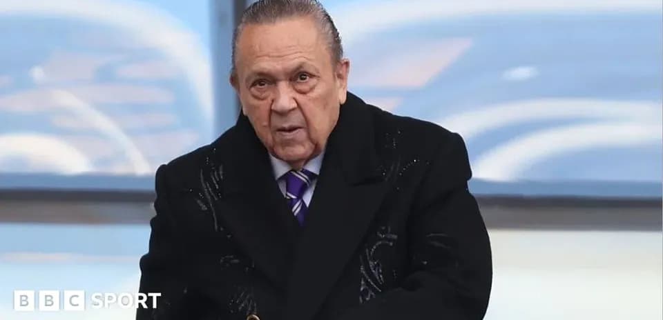 Hombre con abrigo oscuro en un evento deportivo