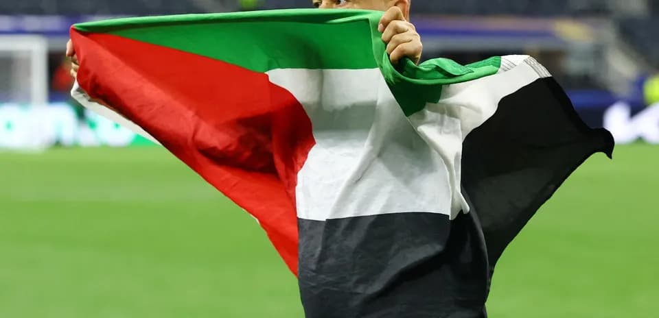 Hombre sosteniendo bandera de Palestina en el campo