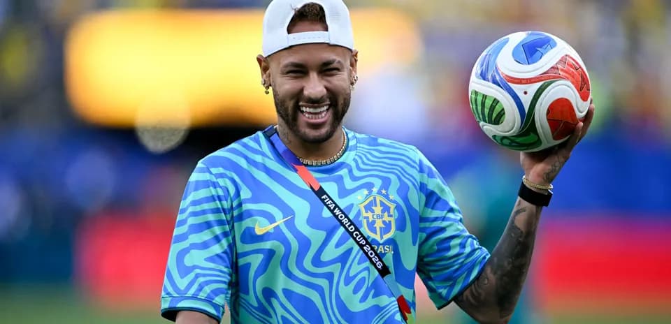 Neymar sosteniendo un balón en el campo de fútbol