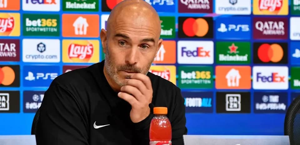 Entrenador en conferencia de prensa con patrocinadores detrás