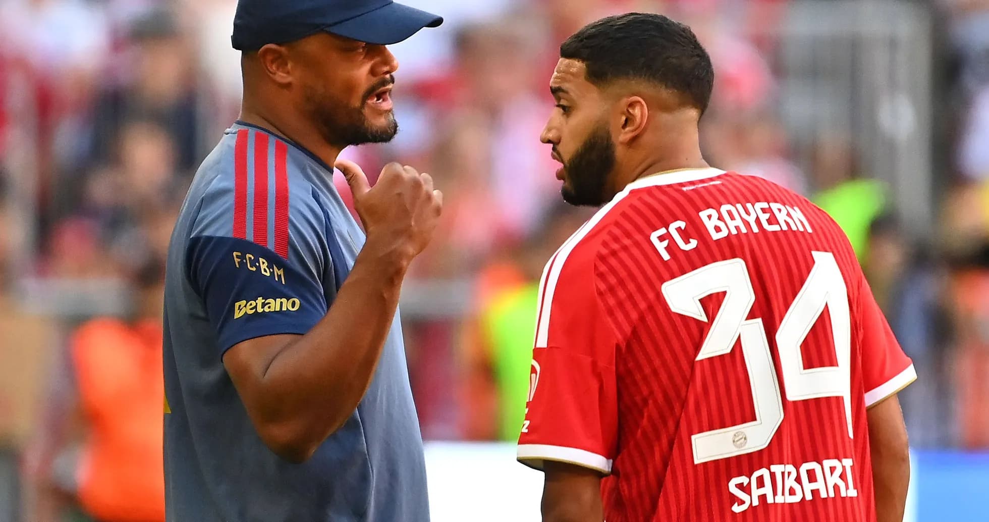 Entrenador hablando con jugador de FC Bayern en el campo