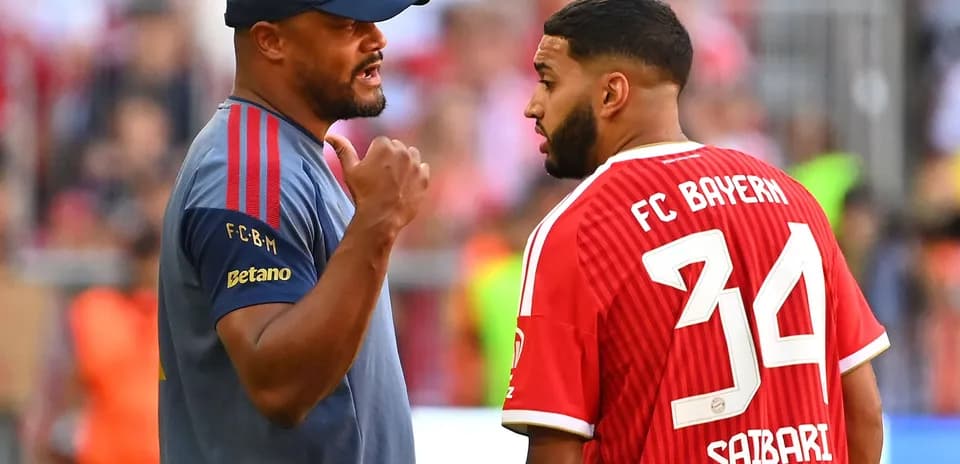 Entrenador hablando con jugador de FC Bayern en el campo
