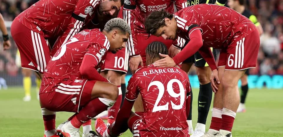 Jugadores de Liverpool rodeando a compañero caído