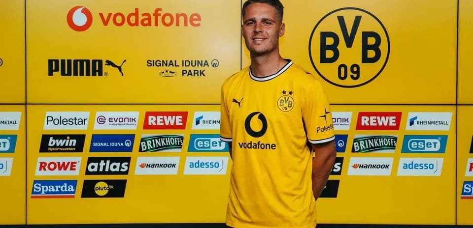 Jugador posando en presentación oficial con camiseta amarilla