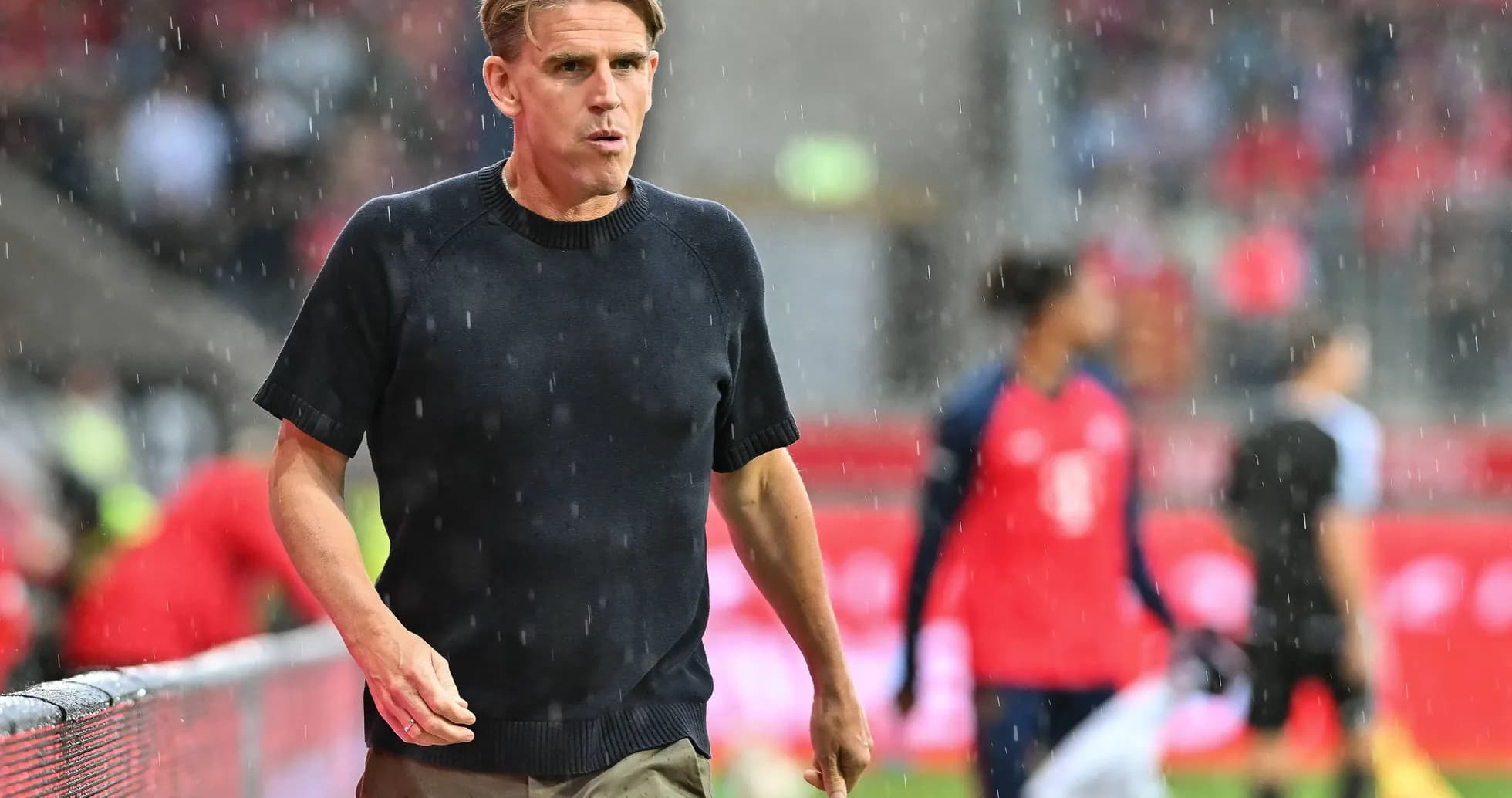 Entrenador caminando por la línea de banda bajo la lluvia