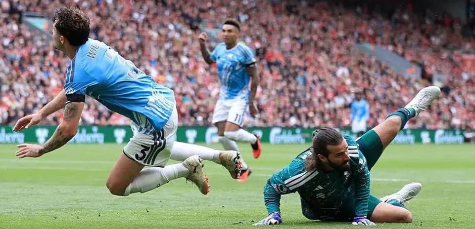 Jugador cayendo mientras el portero atrapa el balón
