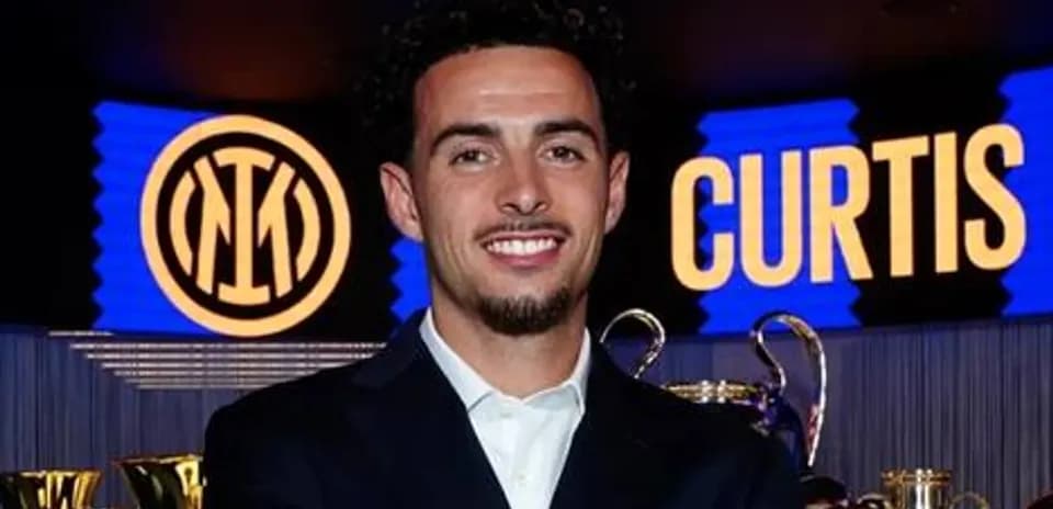 Jugador sonriendo frente a trofeos y logo de Inter