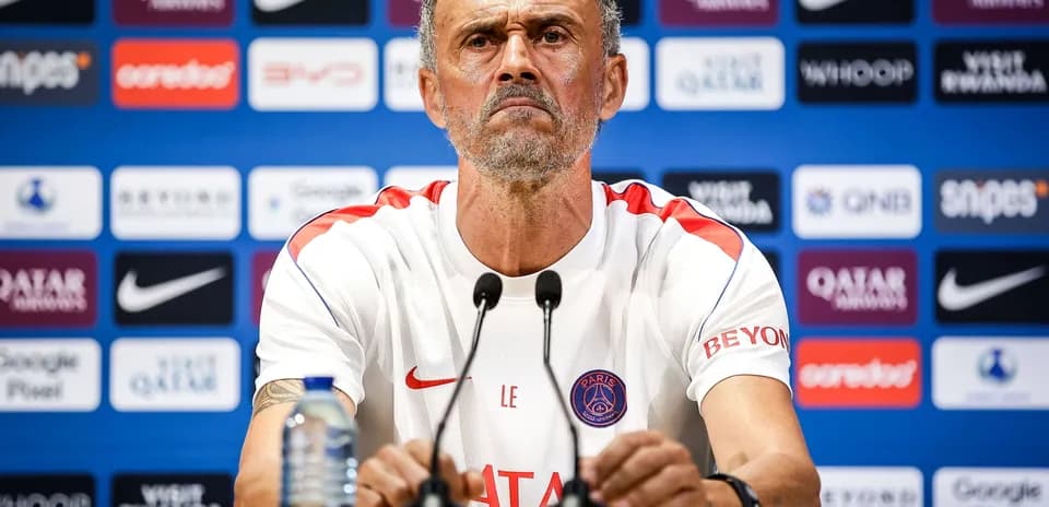 Entrenador en conferencia de prensa con logotipo de PSG