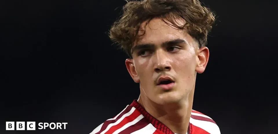 Jugador de fútbol con camiseta roja mirando hacia atrás