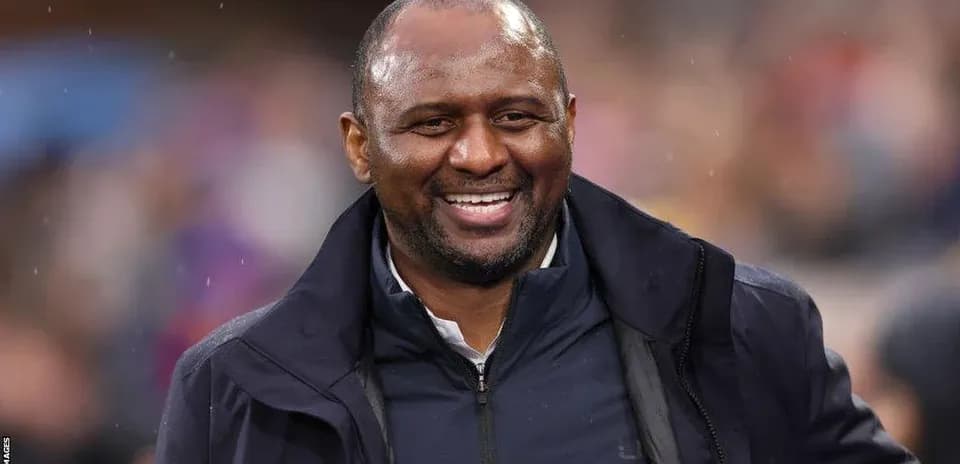 Entrenador sonriendo en el banquillo del estadio
