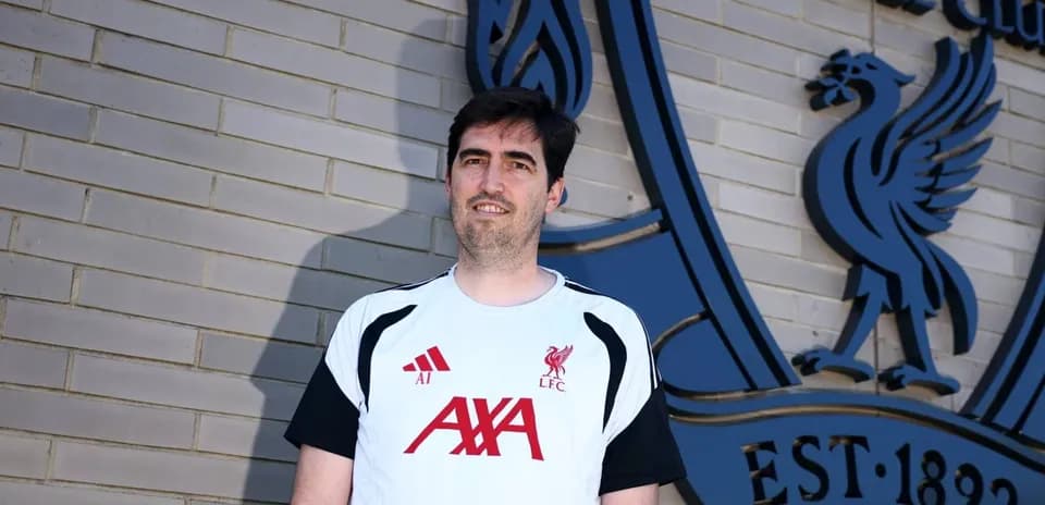 Entrenador posando frente al escudo de Liverpool