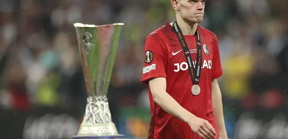 Jugador caminando junto al trofeo de la UEFA Europa League
