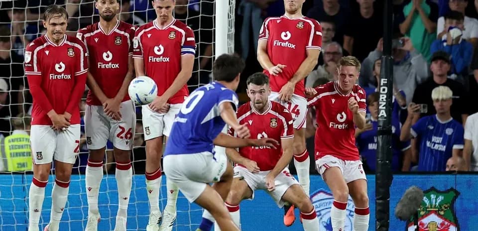 Jugador lanzando un tiro libre frente a la barrera