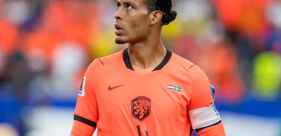 Jugador de fútbol con camiseta naranja observando el partido