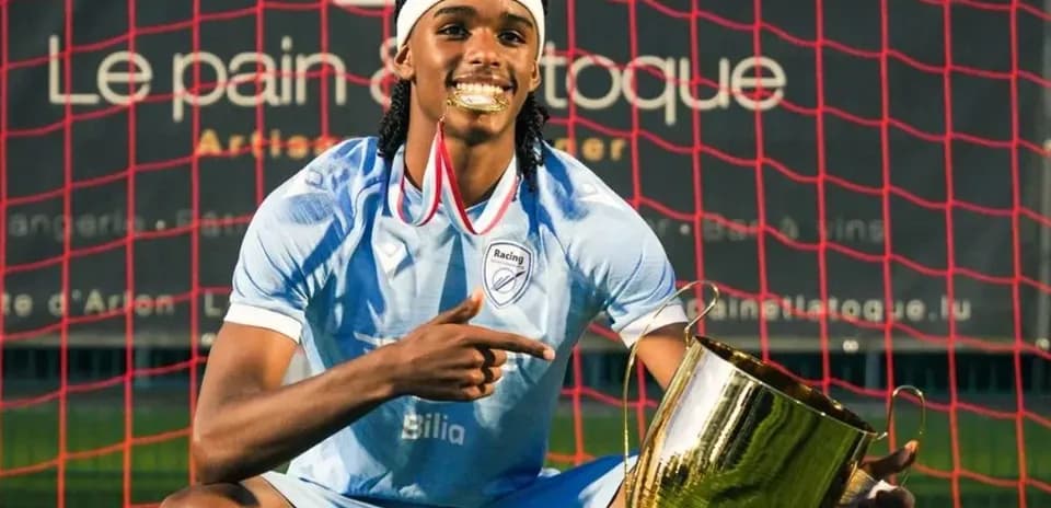 Jugador sosteniendo trofeo en campo de fútbol