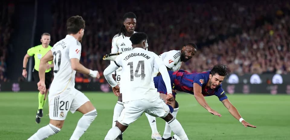 Jugador de Barcelona cayendo ante defensores del Real Madrid
