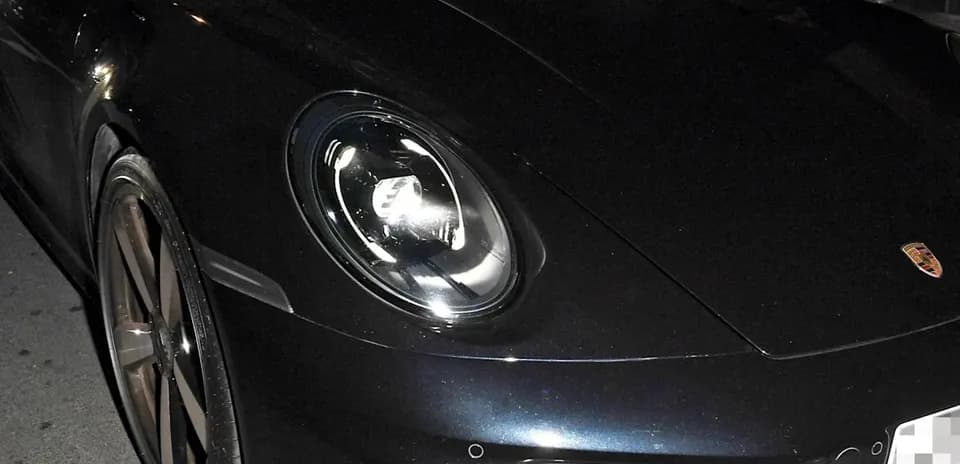 Dos personas dentro de un Porsche negro en la calle