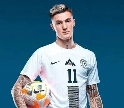 Jugador sosteniendo un balón en uniforme de fútbol