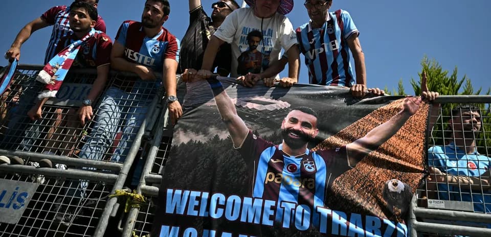 Aficionados sosteniendo una pancarta de bienvenida