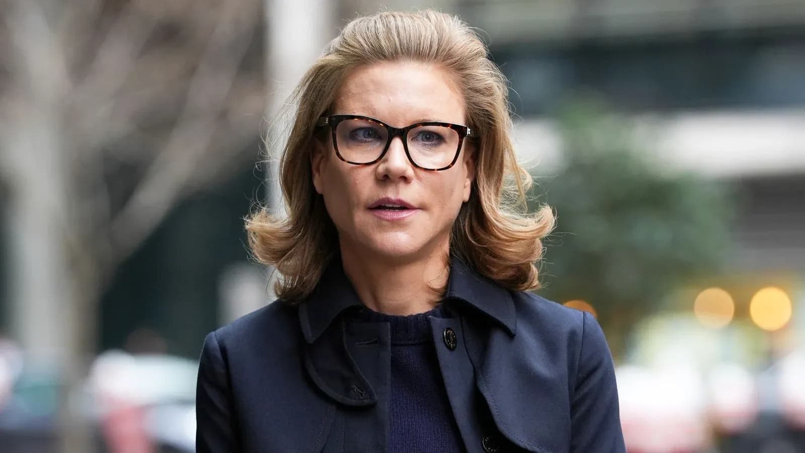 Mujer con gafas y abrigo oscuro en la calle