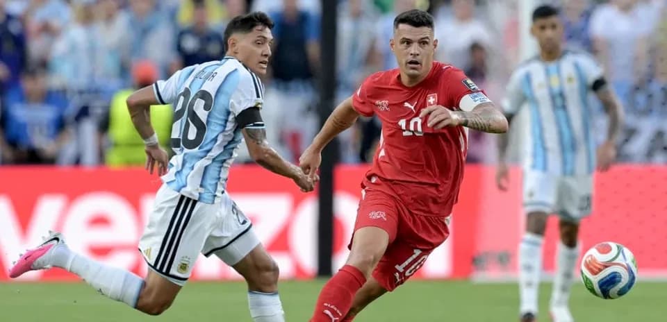 Jugador de Suiza driblando ante defensor argentino en partido