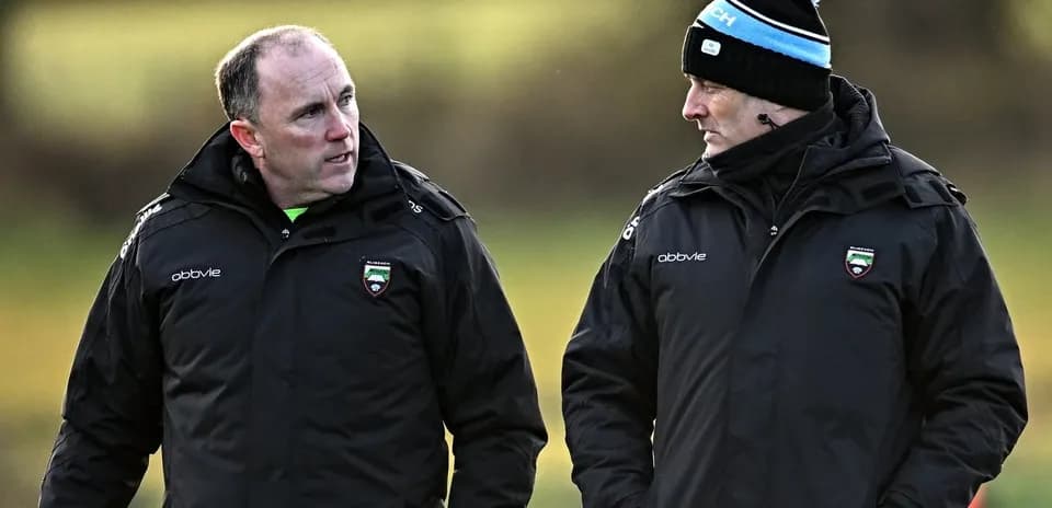 Dos entrenadores conversando en el campo de entrenamiento