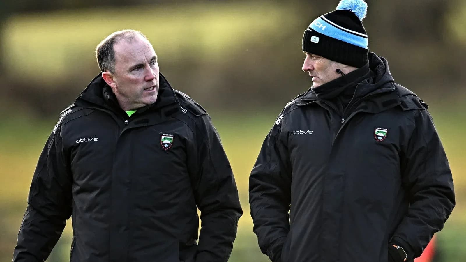Dos entrenadores conversando en el campo de entrenamiento