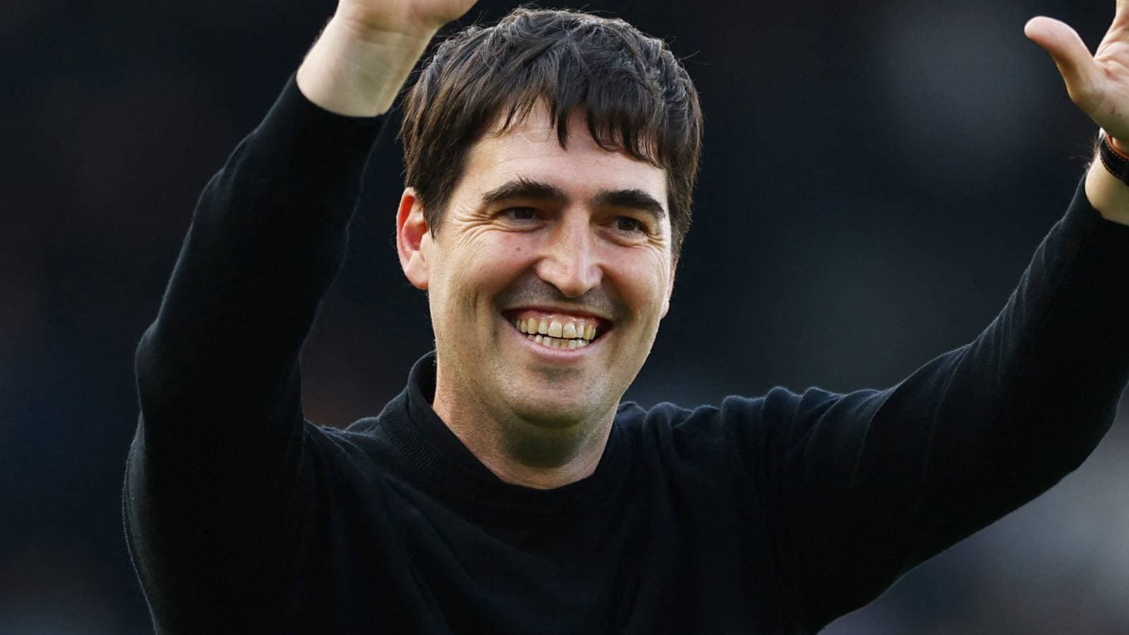 Entrenador sonriendo y saludando al público