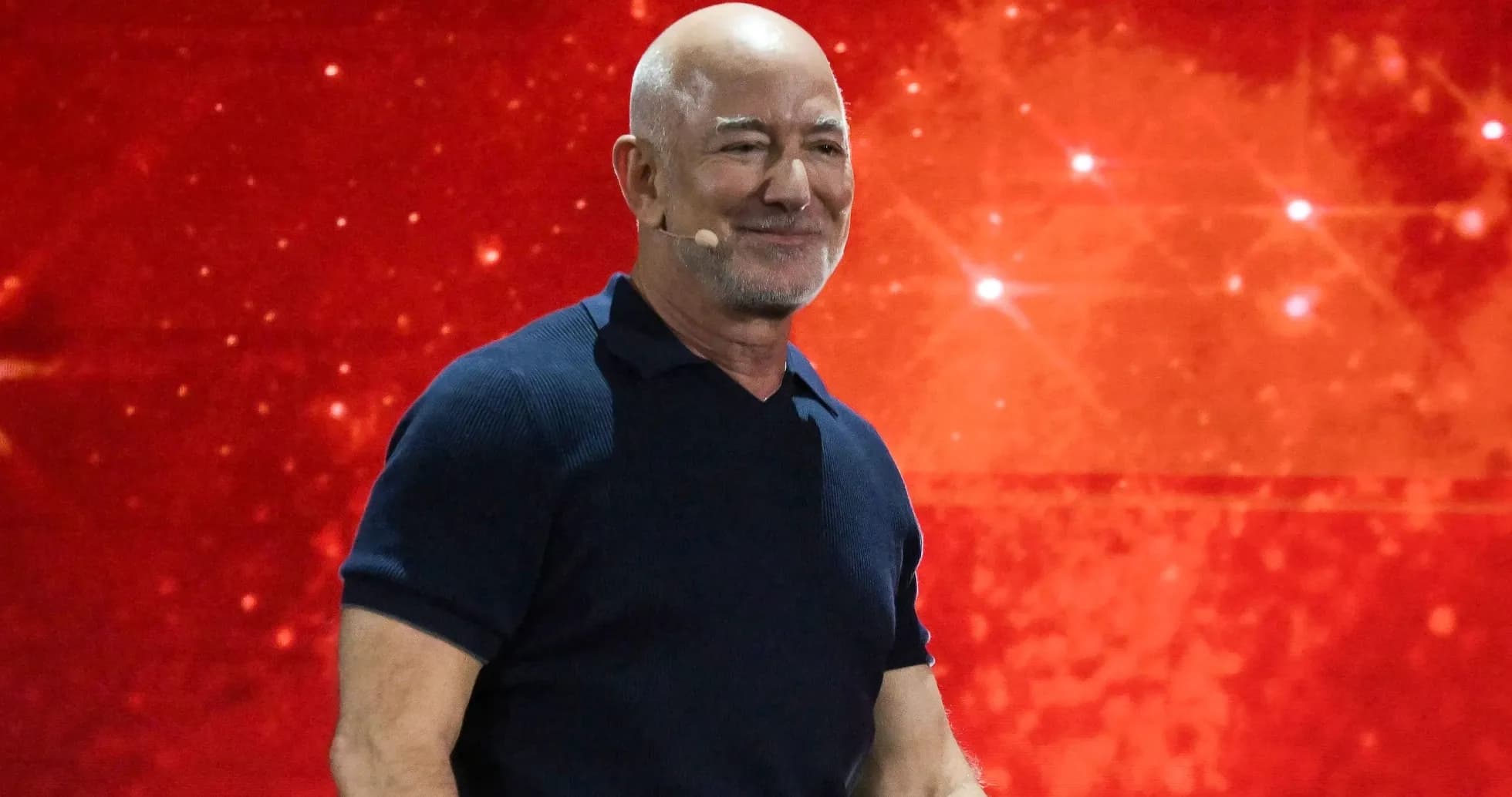 Hombre con micrófono en escenario con fondo rojo