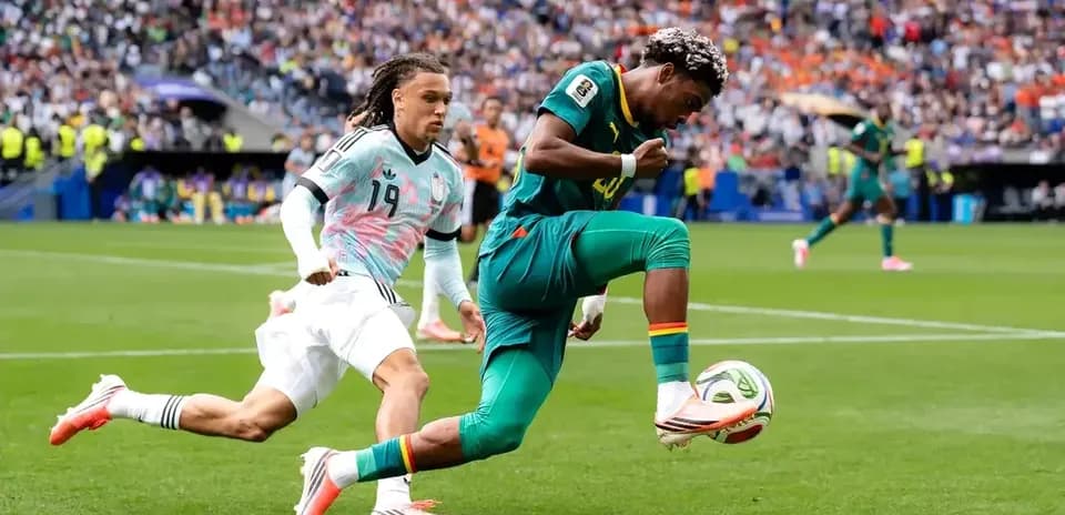 Jugador de Camerún controla el balón mientras es perseguido