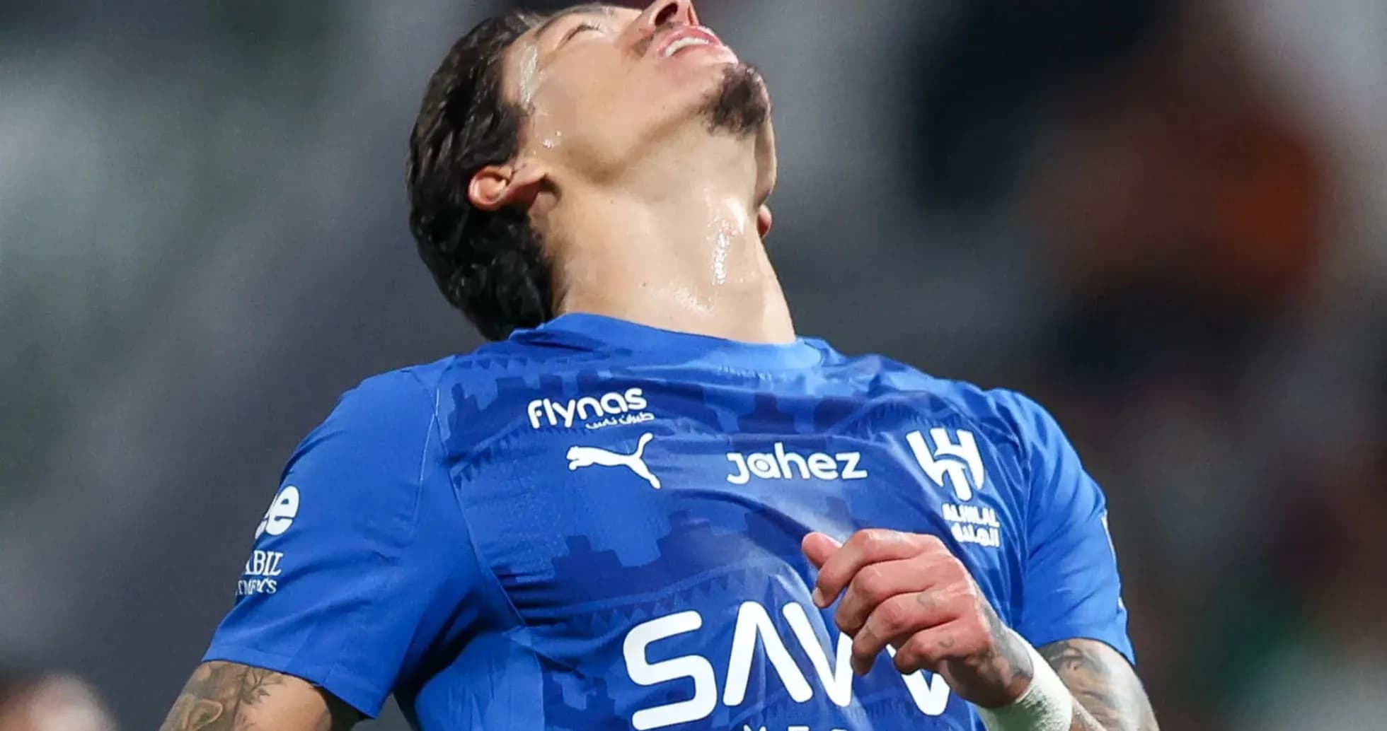 Jugador de fútbol en camiseta azul mirando hacia arriba