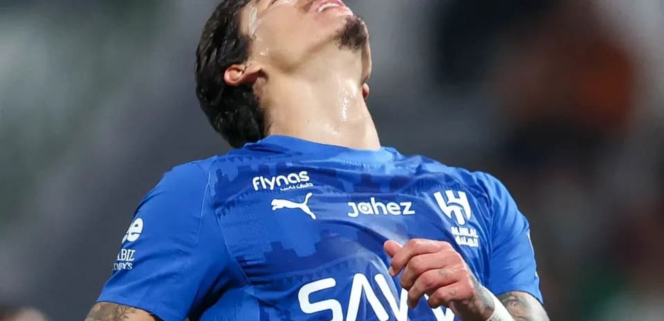 Jugador de fútbol en camiseta azul mirando hacia arriba