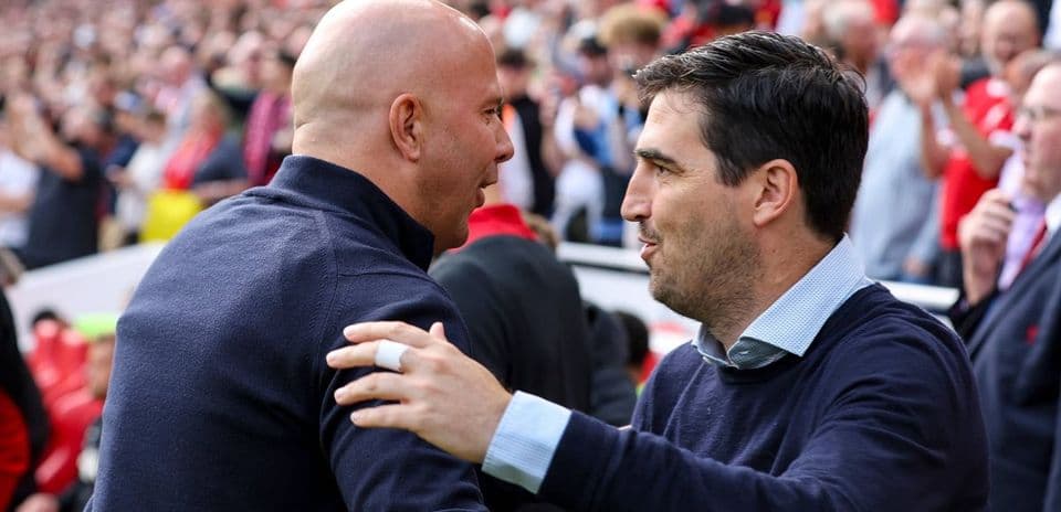 Dos entrenadores saludándose en el estadio