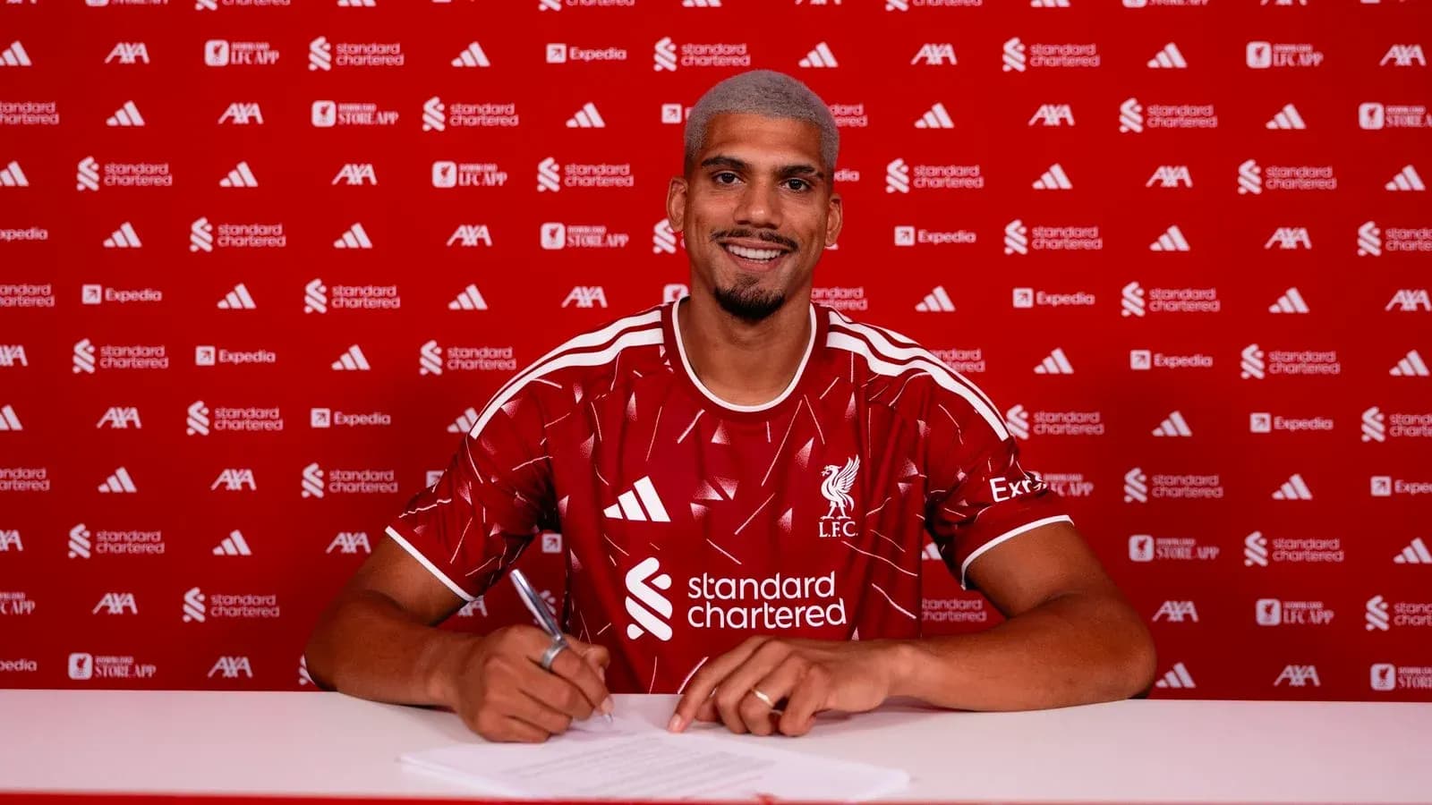 Jugador firmando contrato con Liverpool en conferencia