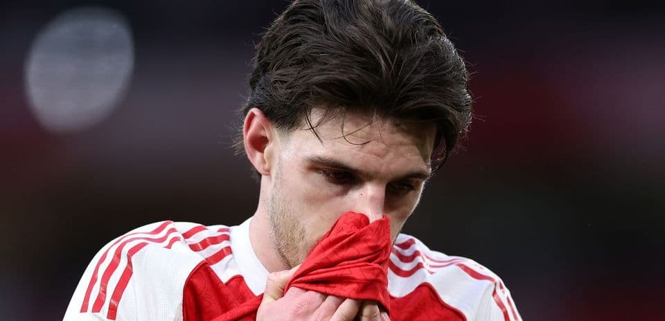 Jugador de fútbol sosteniendo su camiseta con expresión pensativa